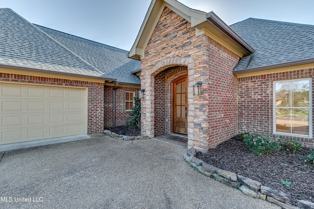 128 Amethyst Ln, Brandon, MS 39047 - view of exterior entry with a shingled roof, brick siding, driveway, and an attached garage
