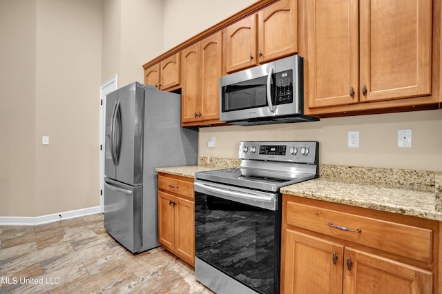 4813 Rosepetal Cv, Southaven, MS 38672 - kitchen with light stone countertops, brown cabinetry, stainless steel appliances, baseboards, and stone finish flooring