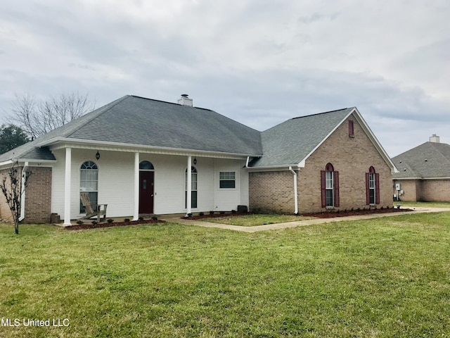 view of front of home featuring a chimney, brick siding, roof with shingles, and a front yard