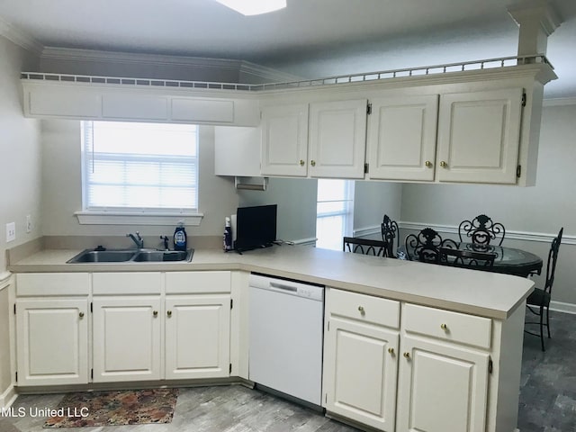 kitchen with a peninsula, white dishwasher, ornamental molding, and a sink