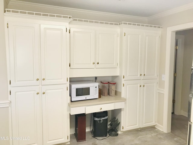 interior space with ornamental molding, light countertops, white cabinetry, and white microwave