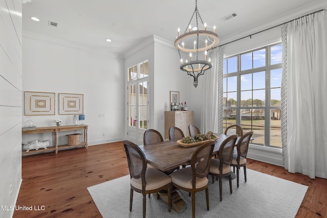 dining room with crown molding, an inviting chandelier, a healthy amount of sunlight, and wood finished floors