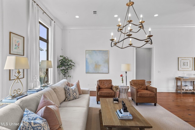 living room with crown molding, a notable chandelier, wood finished floors, and visible vents