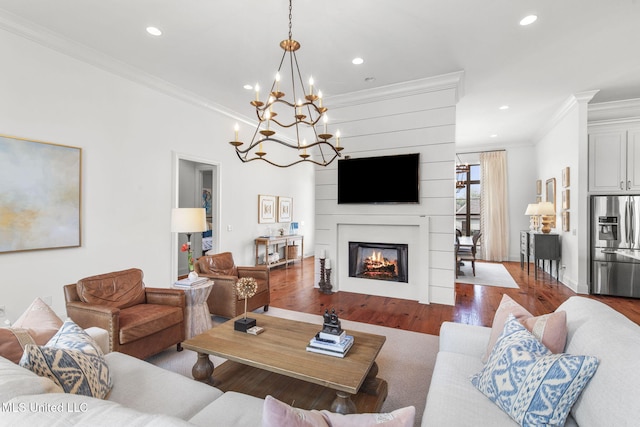 living area with an inviting chandelier, ornamental molding, wood finished floors, and recessed lighting