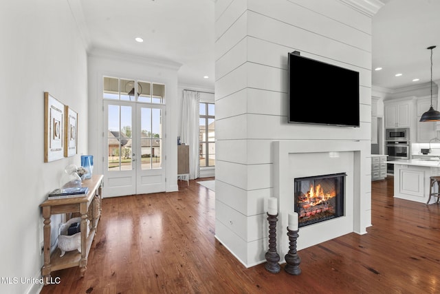 living area featuring crown molding, recessed lighting, a glass covered fireplace, and dark wood-style floors