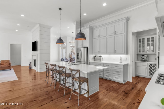 kitchen featuring stainless steel fridge, light countertops, a breakfast bar area, and recessed lighting