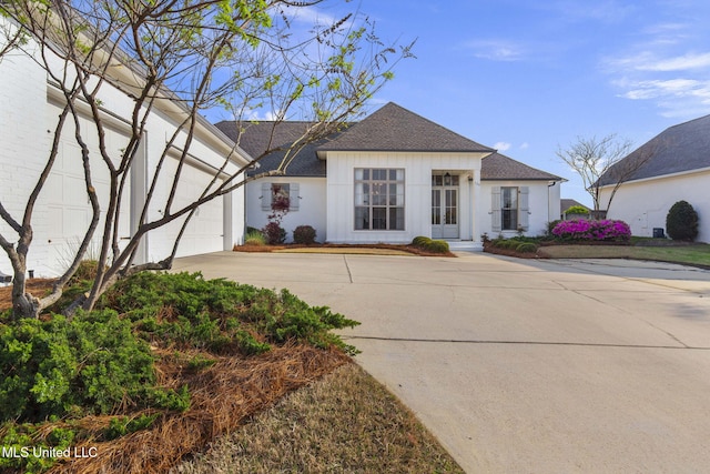 ranch-style house with an attached garage, a shingled roof, and concrete driveway