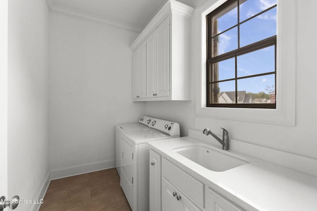 clothes washing area with cabinet space, crown molding, a sink, baseboards, and washing machine and dryer