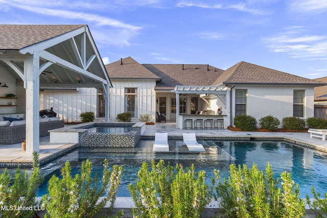 rear view of house featuring an in ground hot tub, roof with shingles, an outdoor pool, outdoor dry bar, and outdoor lounge area