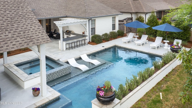 view of pool featuring area for grilling, a pool with connected hot tub, outdoor dry bar, a patio, and a pergola