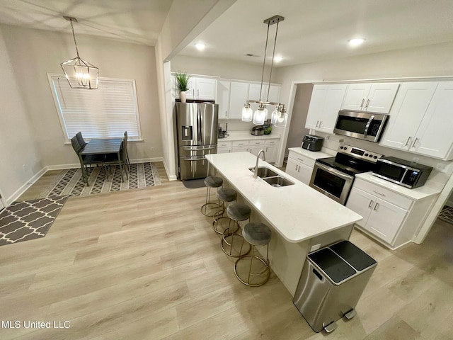 kitchen with appliances with stainless steel finishes, a kitchen island with sink, pendant lighting, and sink