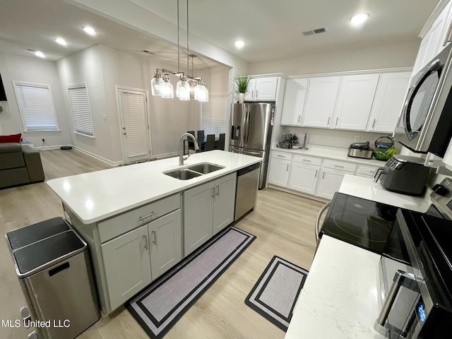 kitchen featuring stainless steel appliances, hanging light fixtures, a chandelier, white cabinets, and sink