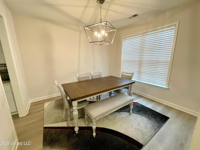 dining space with wood-type flooring and a chandelier