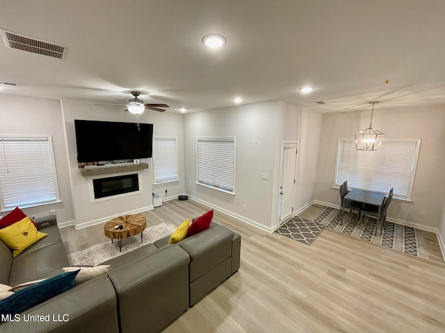 living room with light hardwood / wood-style floors and ceiling fan with notable chandelier