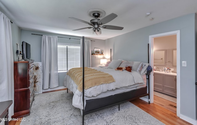 bedroom with light hardwood / wood-style floors, ensuite bathroom, and ceiling fan