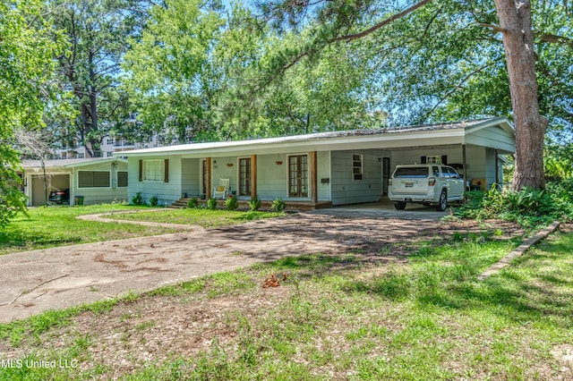 ranch-style house featuring a porch, a front yard, and a carport