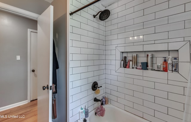 bathroom featuring wood-type flooring and tiled shower / bath