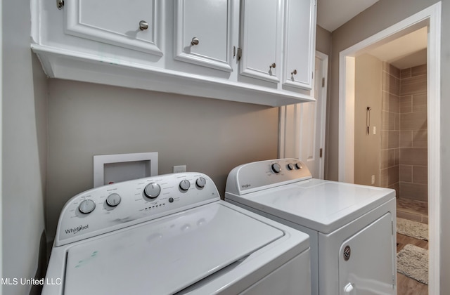 clothes washing area with cabinets, hardwood / wood-style floors, and washer and clothes dryer