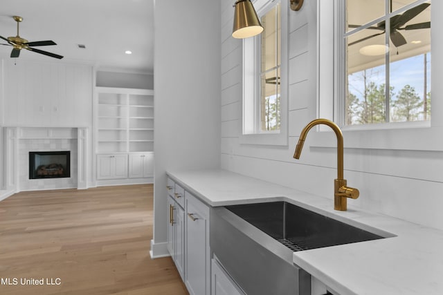 kitchen featuring a ceiling fan, light wood-style floors, white cabinets, and a sink