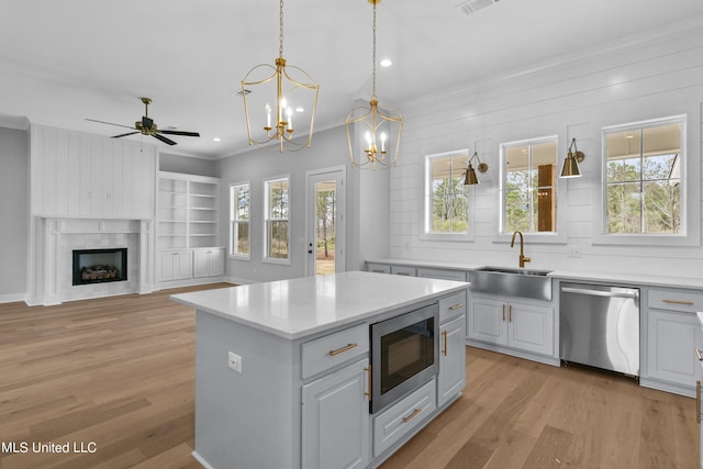 kitchen with built in microwave, light countertops, stainless steel dishwasher, and a center island