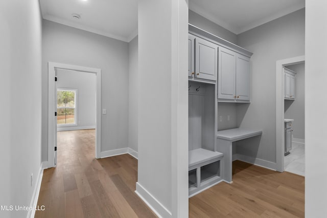 mudroom featuring light wood-style floors, crown molding, and baseboards