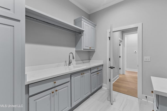 clothes washing area with baseboards, ornamental molding, and a sink