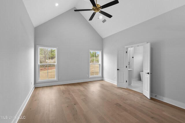 unfurnished bedroom with light wood-type flooring, high vaulted ceiling, baseboards, and visible vents