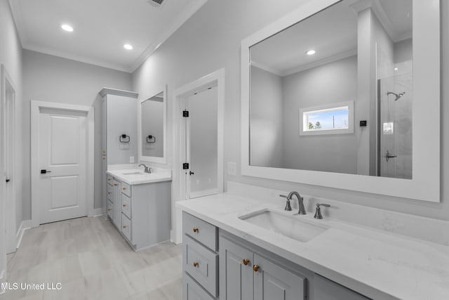 bathroom featuring ornamental molding, two vanities, a sink, and tiled shower