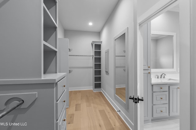 walk in closet featuring light wood-type flooring and a sink