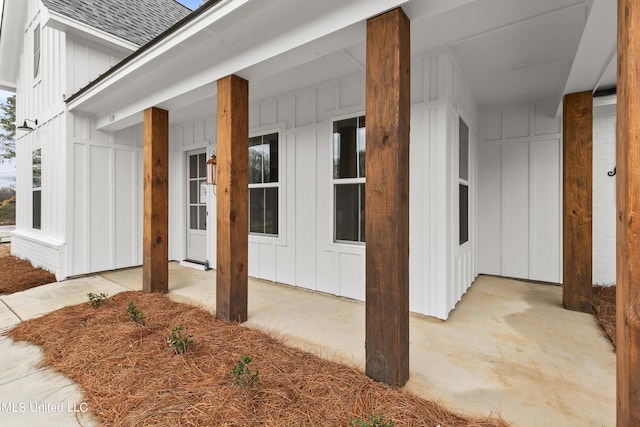 view of exterior entry featuring roof with shingles and board and batten siding