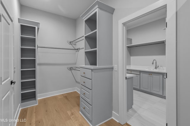 walk in closet featuring a sink and light wood-style flooring