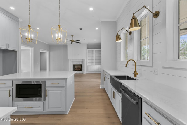 kitchen with a sink, white cabinets, light countertops, stainless steel dishwasher, and built in microwave