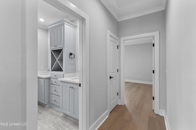 hall featuring light wood-type flooring, visible vents, crown molding, and baseboards