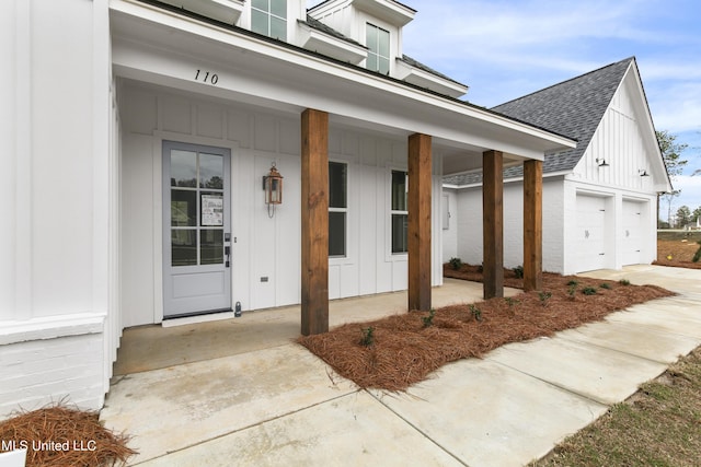 property entrance featuring board and batten siding, roof with shingles, a porch, and a garage