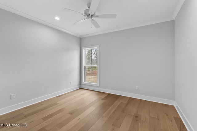 spare room with ornamental molding, light wood-style floors, baseboards, and a ceiling fan