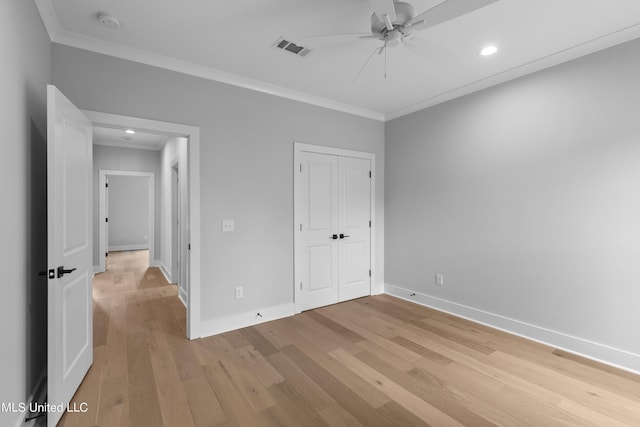 unfurnished bedroom featuring baseboards, light wood finished floors, visible vents, and crown molding