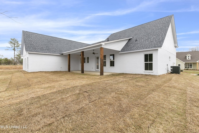 rear view of property featuring central AC, a shingled roof, a ceiling fan, a yard, and a patio area