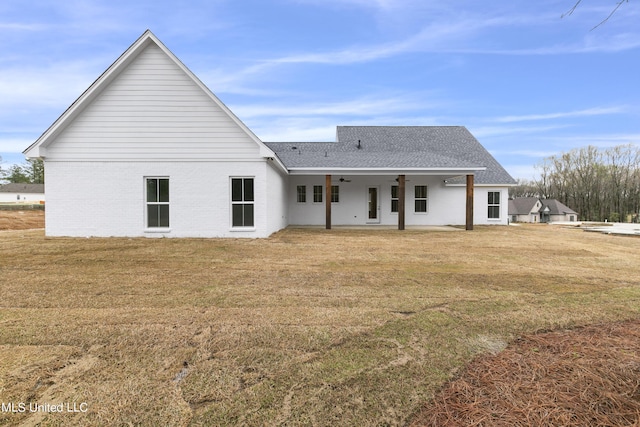 back of property featuring a patio, a lawn, a ceiling fan, and roof with shingles