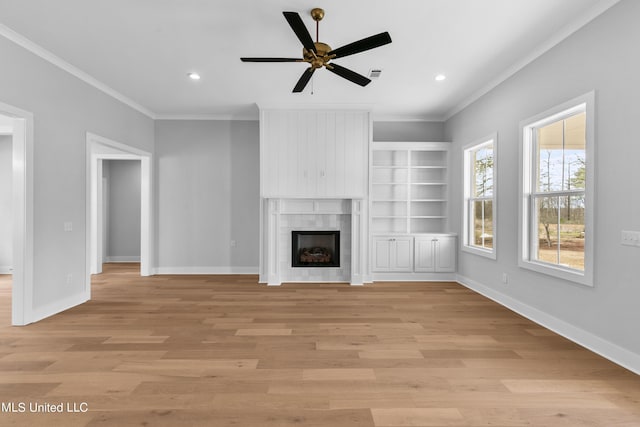 unfurnished living room featuring light wood finished floors, a fireplace, baseboards, and ornamental molding