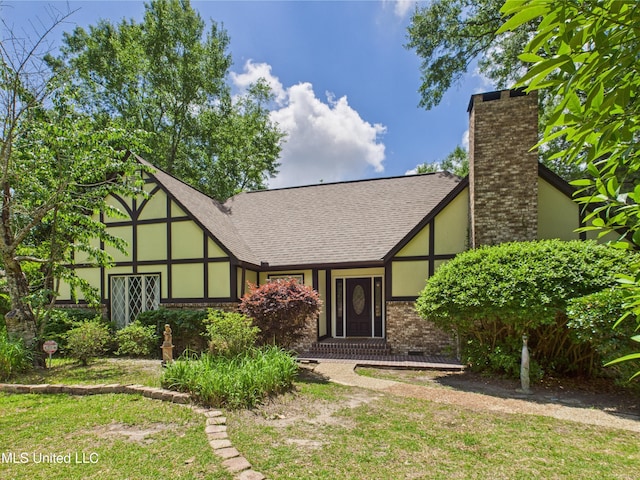 view of front of house featuring brick siding, a chimney, a shingled roof, and stucco siding