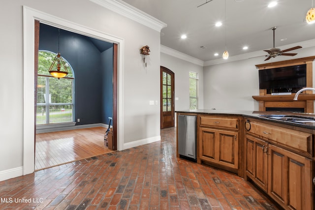 kitchen with brick floor, a sink, baseboards, brown cabinets, and crown molding