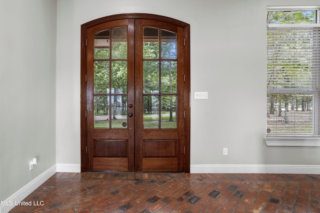 foyer with brick floor, baseboards, and french doors