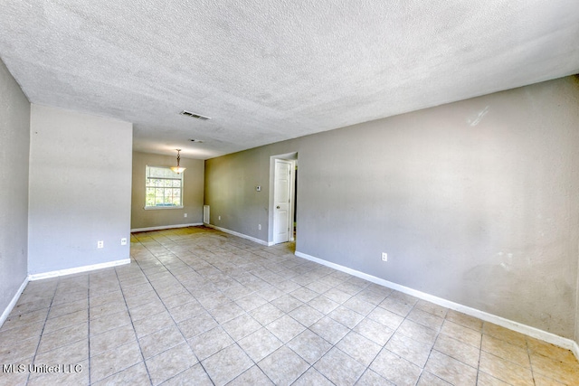 tiled empty room featuring a textured ceiling