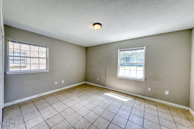 empty room featuring a textured ceiling, a healthy amount of sunlight, and light tile patterned floors