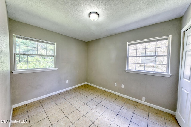 empty room featuring a textured ceiling and light tile patterned floors