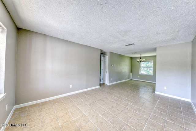 unfurnished room featuring a textured ceiling and an inviting chandelier