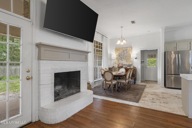 251 Greensview Dr, Brandon, MS 39047 - dining area with wood finished floors, ornamental molding, a brick fireplace, and a chandelier