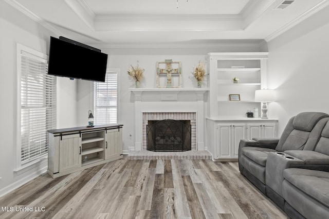 living room featuring a raised ceiling, light wood-style flooring, and crown molding