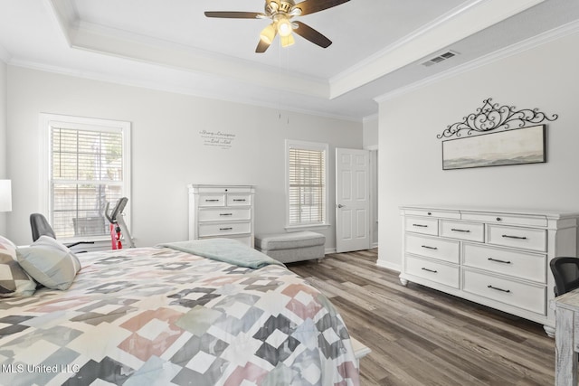 bedroom featuring a tray ceiling, multiple windows, and visible vents