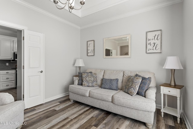 living room featuring a notable chandelier, crown molding, baseboards, and wood finished floors